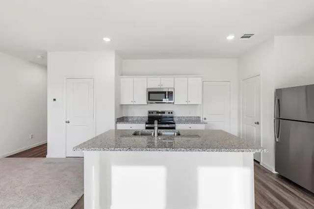 a kitchen with a sink dishwasher a stove and a refrigerator with wooden floor