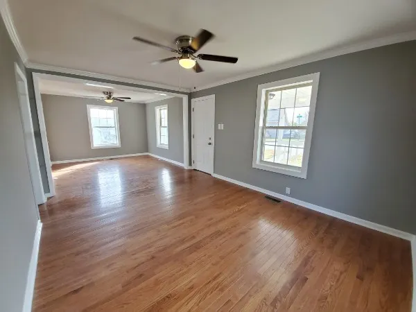 a view of an empty room with wooden floor and a window