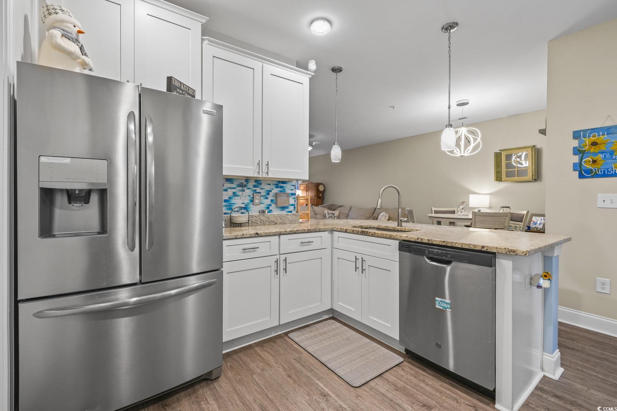 124 Birch N Coppice Drive, Unit 3 Surfside Beach, SC 29575 - Photo 6 of 40 Kitchen with appliances with stainless steel finishes, white cabinets, a peninsula, backsplash, and pendant lighting