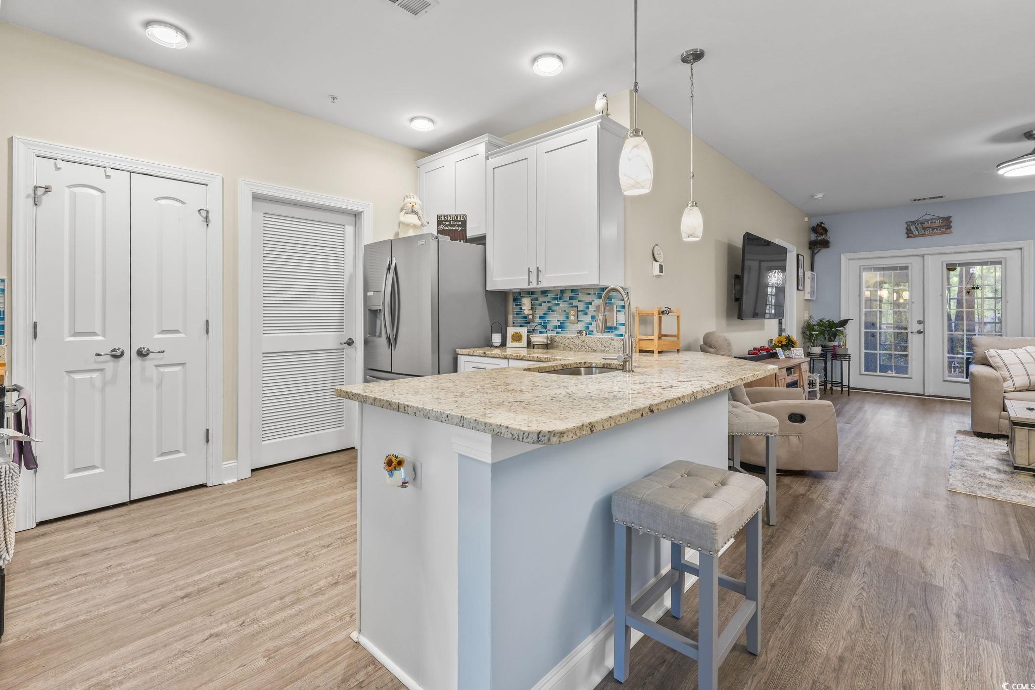 124 Birch N Coppice Drive, Unit 3 Surfside Beach, SC 29575 - Photo 40 of 40 Kitchen with a kitchen breakfast bar, open floor plan, a peninsula, french doors, and light wood-style flooring