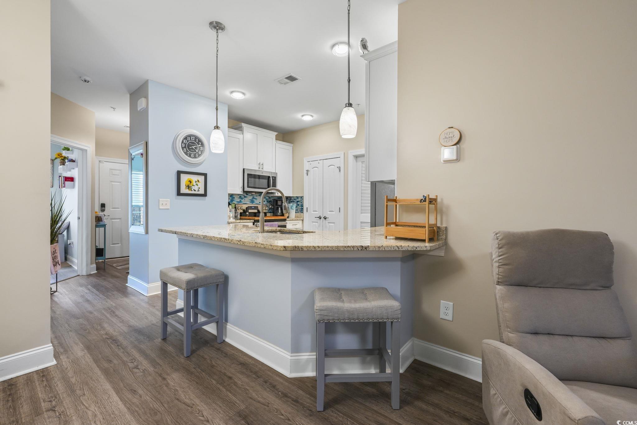 124 Birch N Coppice Drive, Unit 3 Surfside Beach, SC 29575 - Photo 8 of 40 Kitchen with a breakfast bar, light stone counters, a peninsula, white cabinets, and decorative light fixtures