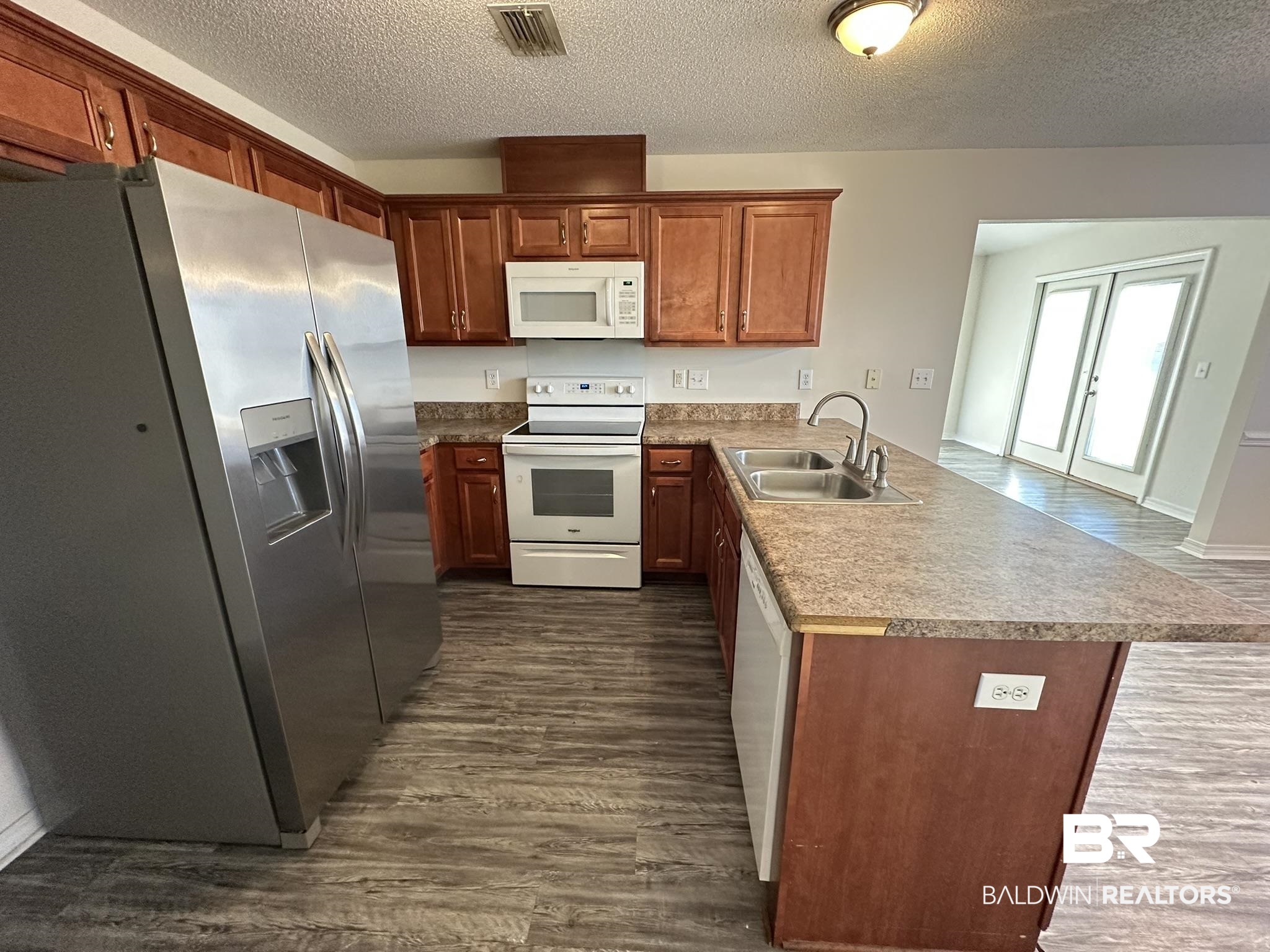 1760 Abbey Loop Foley, AL 36535 - Photo 8 of 41 Kitchen featuring white appliances, a peninsula, a textured ceiling, dark wood-style floors, and brown cabinetry
