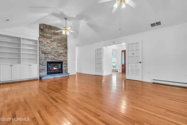 a view of an empty room with wooden floor fireplace and a window