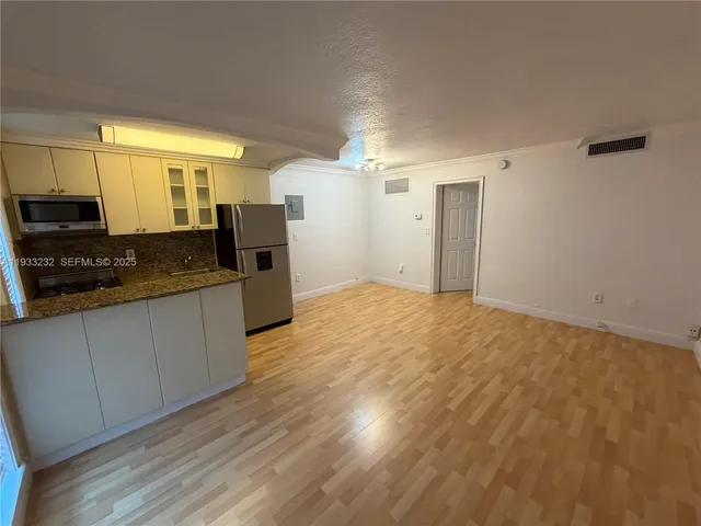 a kitchen with granite countertop a sink cabinets and wooden floor