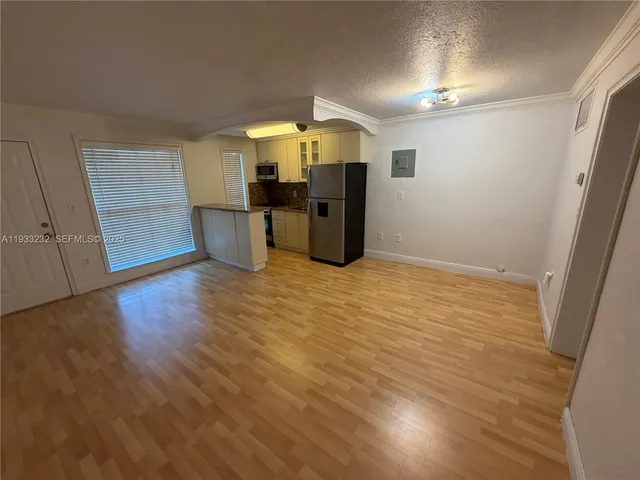 an empty room with wooden floor closet and windows