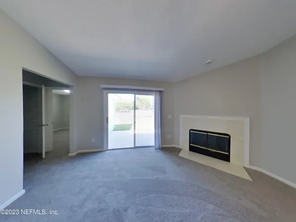 a view of an empty room with a fireplace and a window