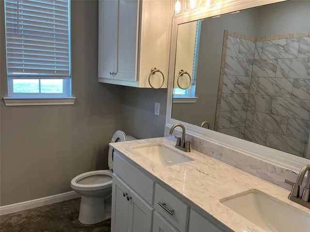 a bathroom with a granite countertop sink toilet and mirror