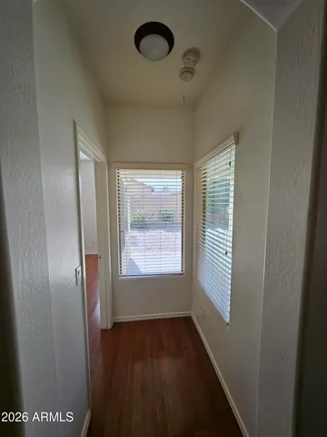 a view of an empty room with a window and wooden floor
