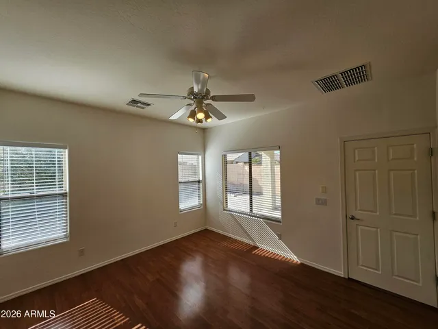 an empty room with wooden floor fan and windows
