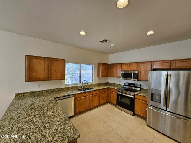 a kitchen with stainless steel appliances granite countertop a sink stove and refrigerator