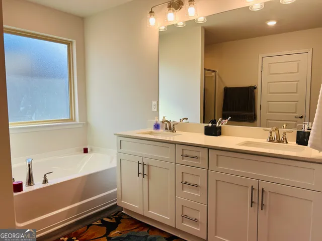 a bathroom with a double vanity sink a mirror and a bathtub