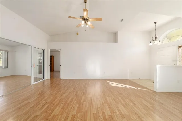 a view of an empty room with wooden floor and a kitchen