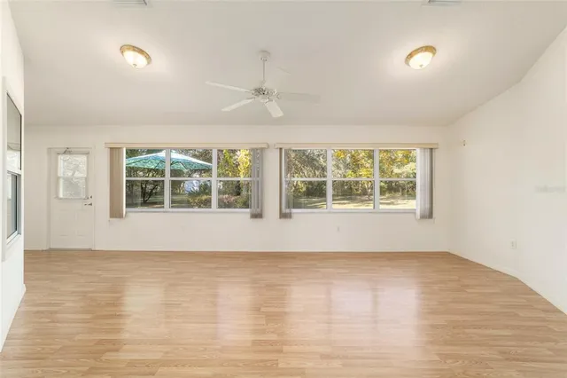 a view of an empty room with a window and wooden floor