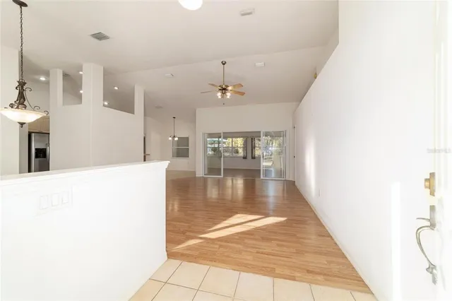 a view of an empty room and window chandelier and wooden floor