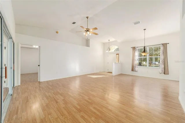 a view of an empty room with chandelier fan and fire place