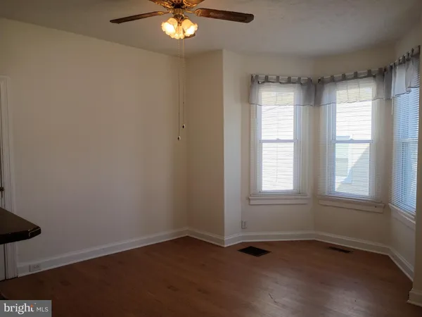 an empty room with wooden floor ceiling fan and windows