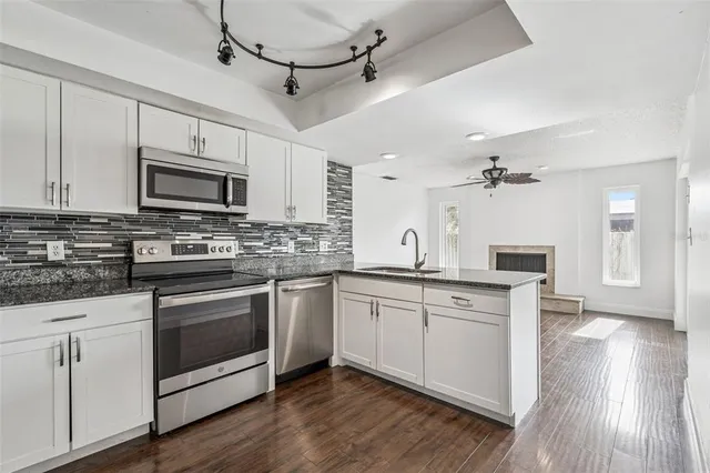 a kitchen with granite countertop a sink cabinets and stainless steel appliances
