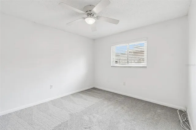 an empty room with a window and a fan