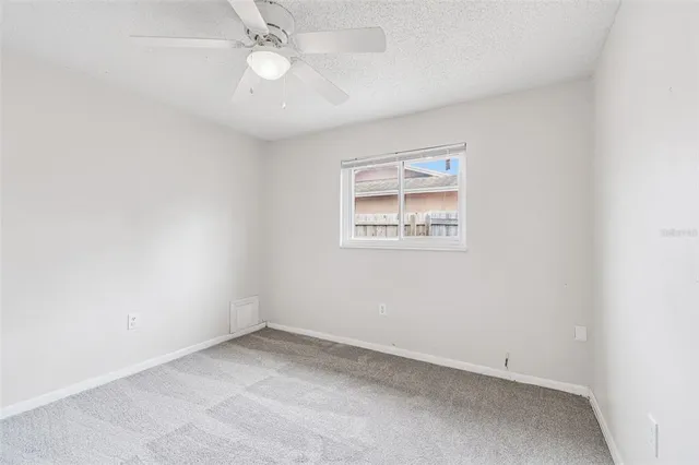 an empty room with a ceiling fan and a window