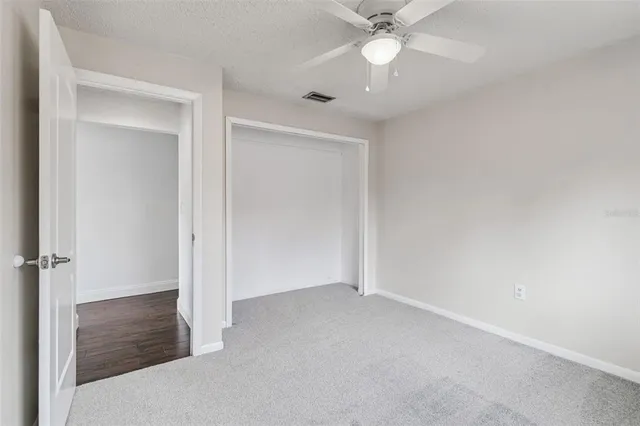 an empty room with a ceiling fan and carpet