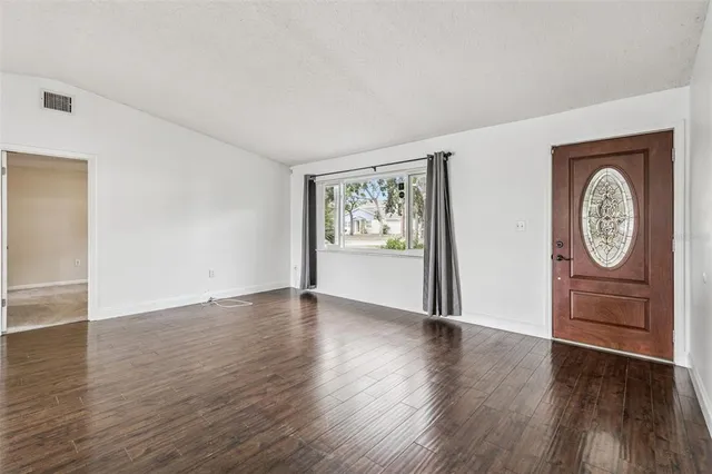 an empty room with wooden floor cabinet and mirror
