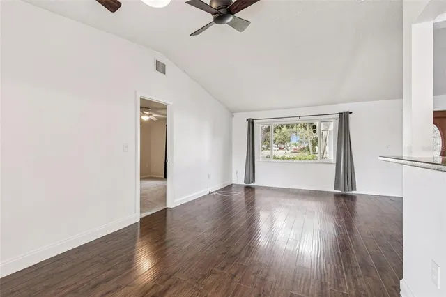 an empty room with wooden floor and a ceiling fan