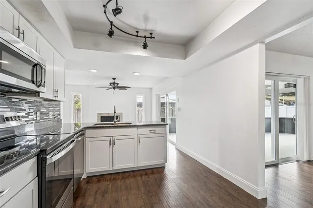 a kitchen with stainless steel appliances granite countertop a sink cabinets and wooden floor