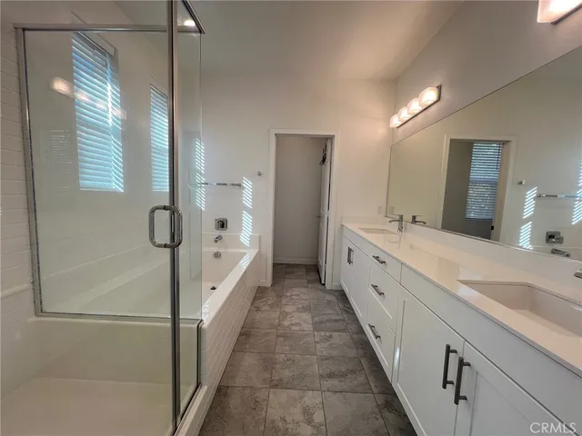 a large white bathroom with a double vanity sink a mirror and a bathtub
