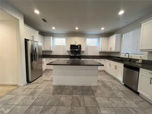 a large kitchen with a large counter top stainless steel appliances and cabinets