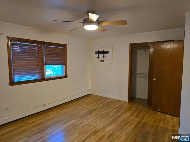 a view of an empty room with window and wooden floor