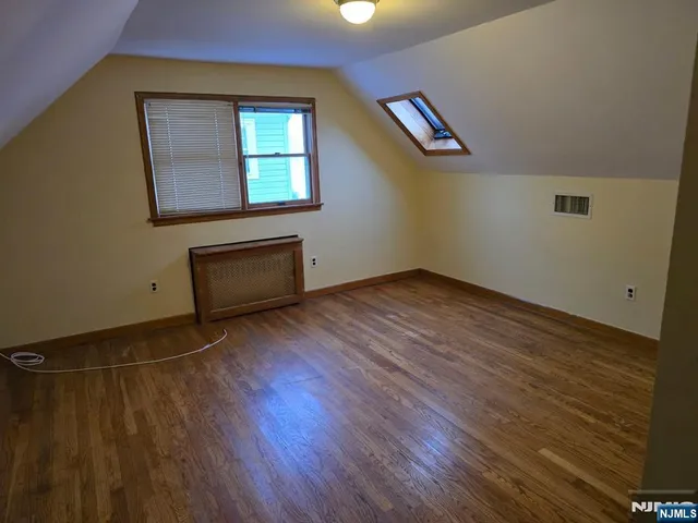 an empty room with wooden floor cabinet and windows