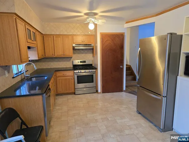 a kitchen with stainless steel appliances granite countertop a refrigerator a stove and a sink