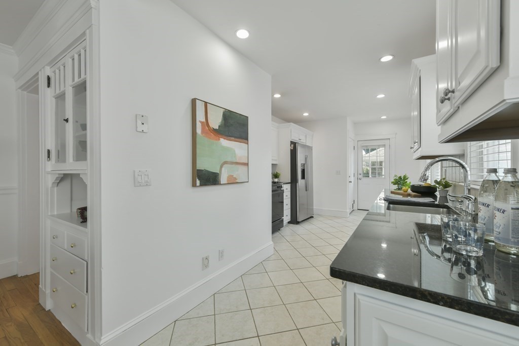 64 Parmenter Road, Unit 1 Waltham, MA 02453 - Photo 9 of 25 a large white kitchen with stainless steel appliances granite countertop a refrigerator and a sink