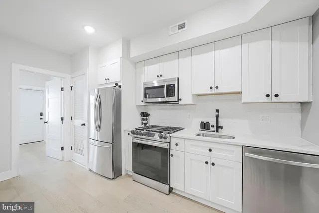 a kitchen with white cabinets and stainless steel appliances