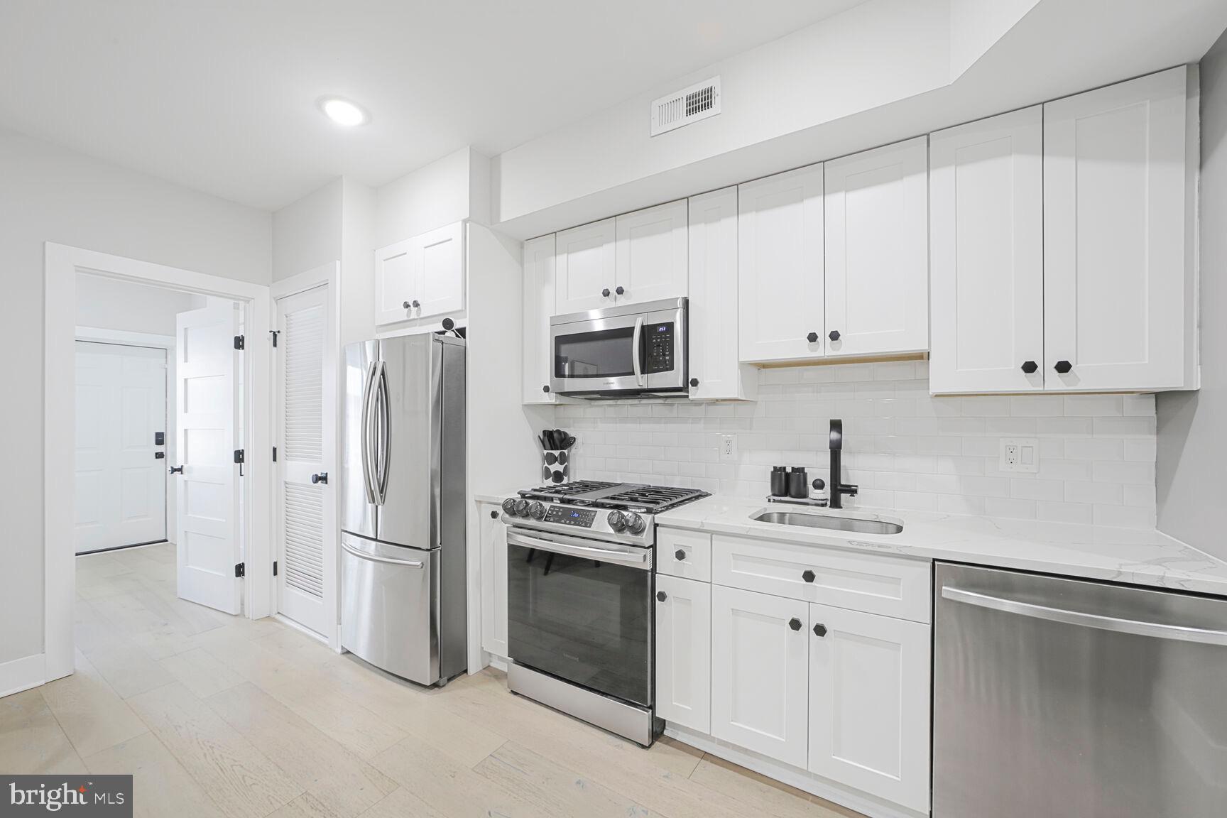 1144 Owen Place Northeast, Unit 1 Washington, DC 20002 - Photo 18 of 27 a kitchen with white cabinets and stainless steel appliances