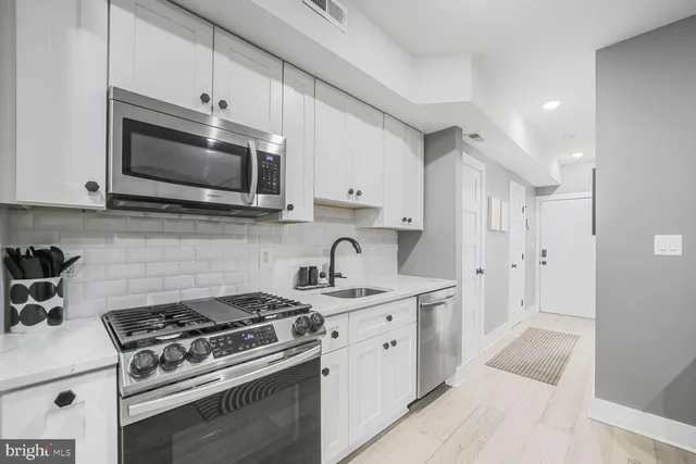 a kitchen with stainless steel appliances granite countertop white cabinets a stove a sink and dishwasher