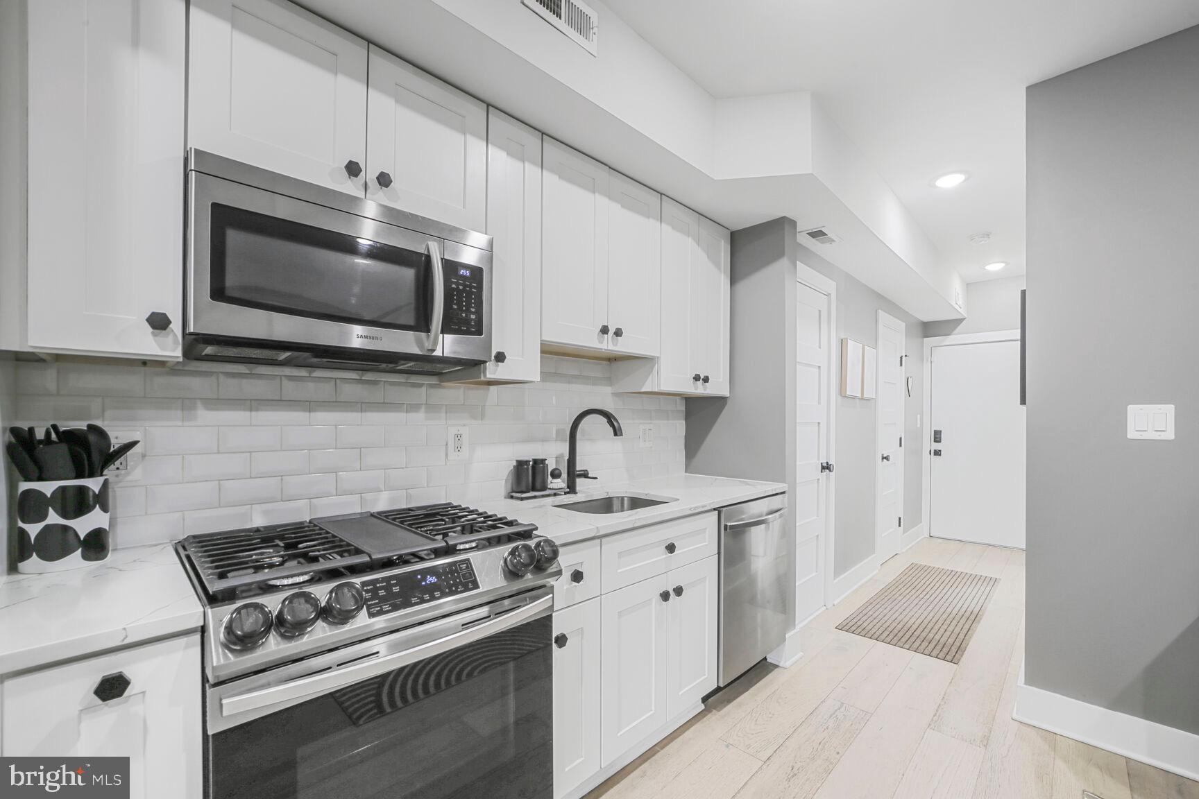 1144 Owen Place Northeast, Unit 1 Washington, DC 20002 - Photo 20 of 27 a kitchen with stainless steel appliances granite countertop white cabinets a stove a sink and dishwasher