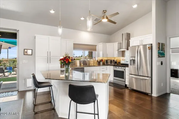 a kitchen with stainless steel appliances a dining table chairs refrigerator and sink