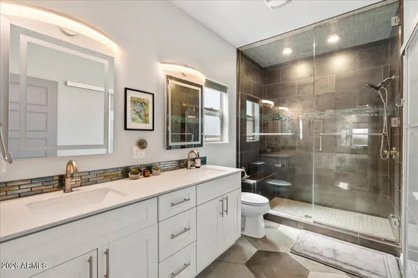 a bathroom with a double vanity sink toilet mirror and shower