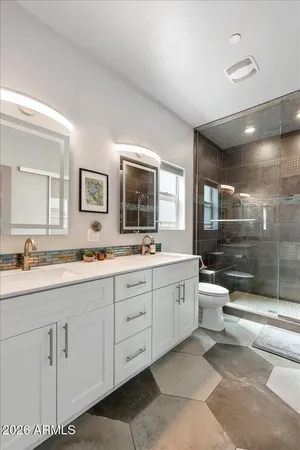 a bathroom with a double vanity sink toilet mirror and shower