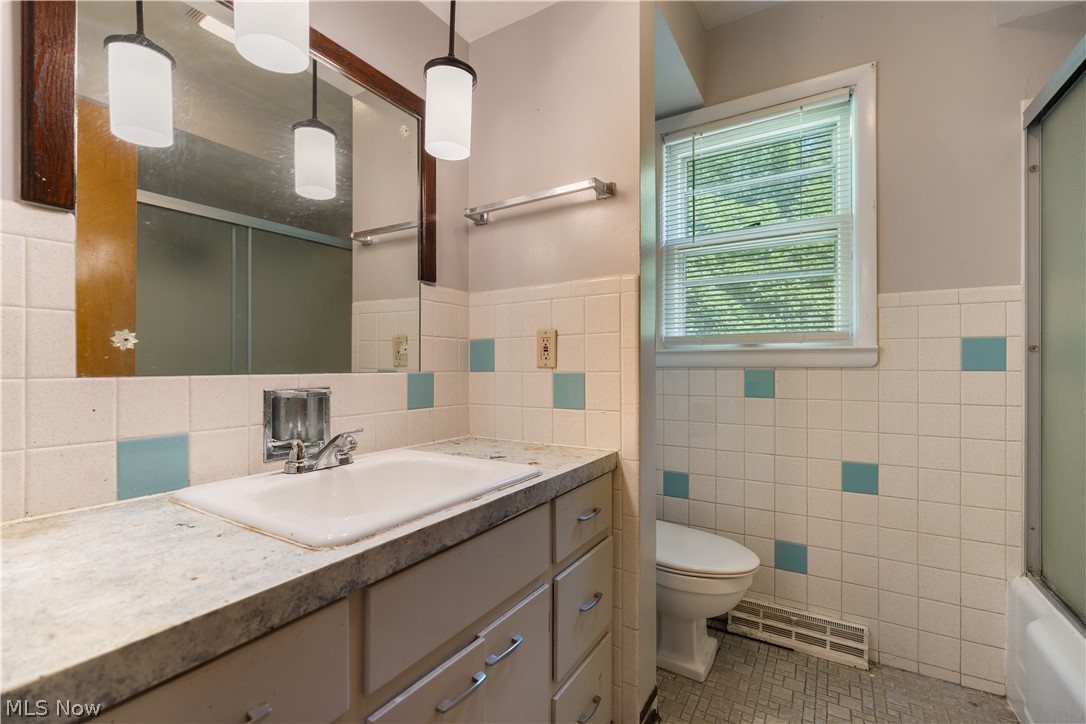 542 Garnette Road Akron, OH 44313 - Photo 22 of 24 Bathroom featuring a single vanity with an integrated sink, a large mirror with a dark wood-finish frame, and pendant lighting