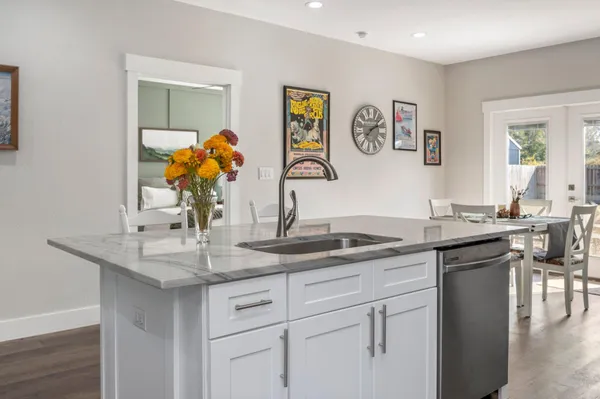 a dining hall with granite countertop a sink and dishwasher with wooden floor