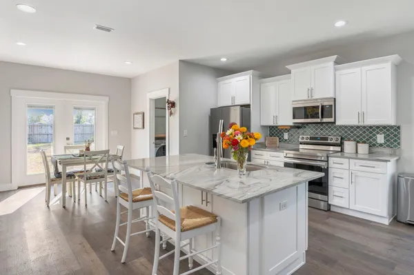 a kitchen with stainless steel appliances granite countertop a stove a sink a microwave a dining table and chairs