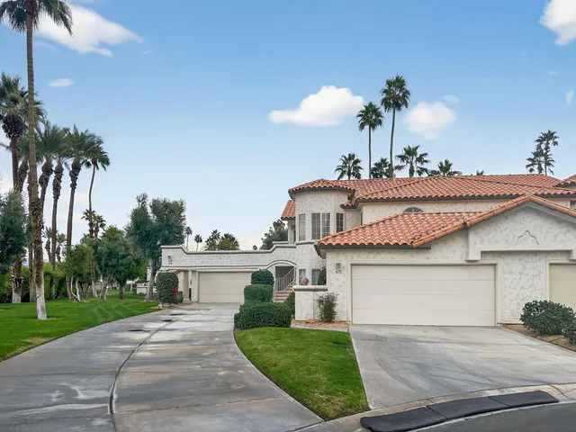 a front view of a house with a yard and palm trees