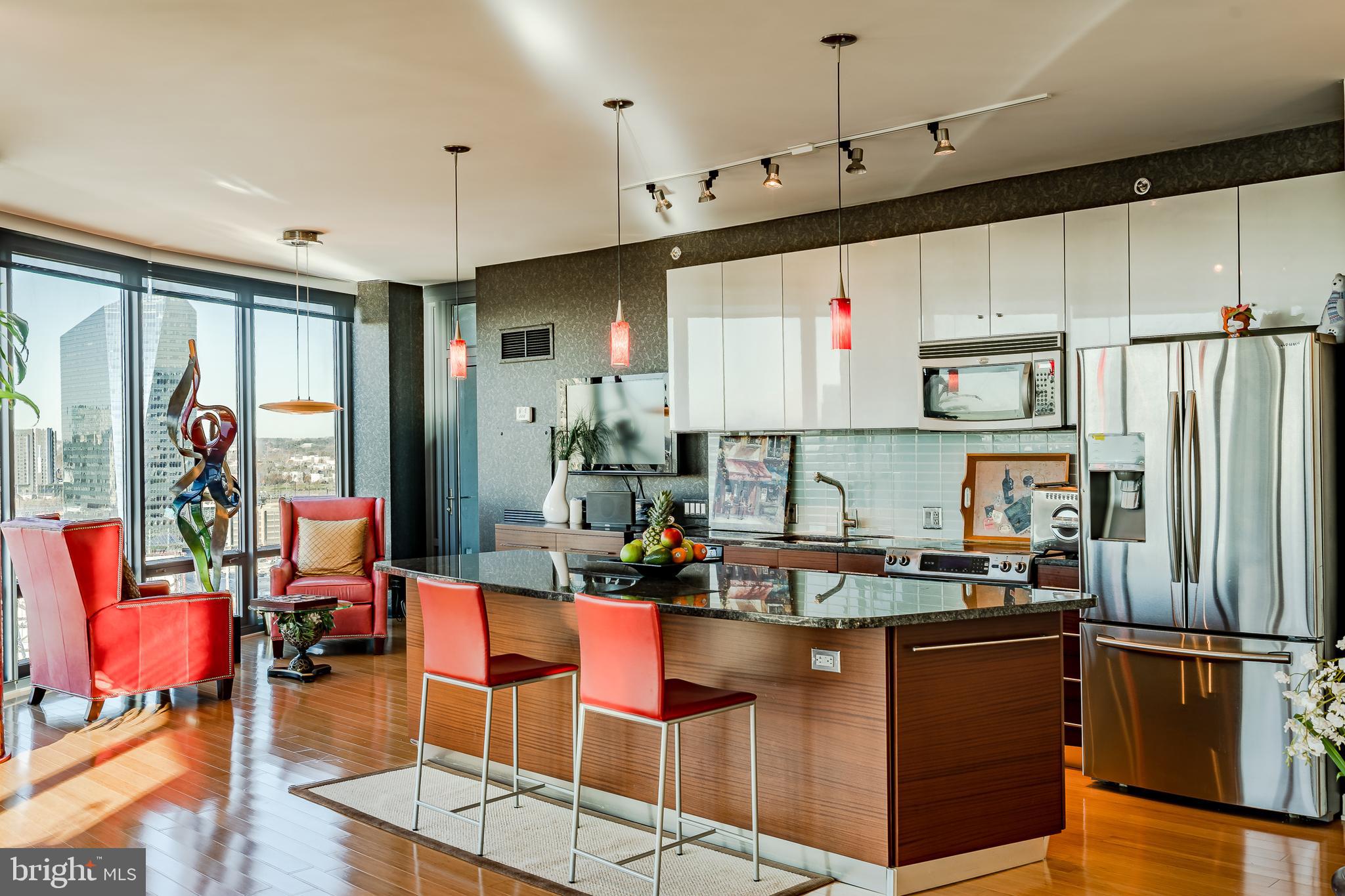 2101-00 Market Street, Unit 1803 Philadelphia, PA 19103 - Photo 12 of 52 a kitchen with stainless steel appliances granite countertop a refrigerator a sink dishwasher a dining table and chairs with wooden floor