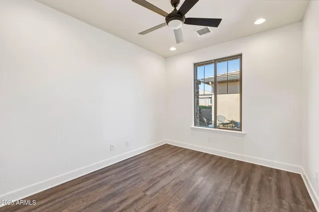 an empty room with a window and ceiling fan