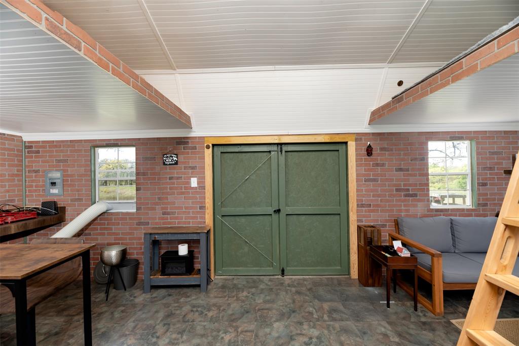 247 Private Road Covington, TX 76636 - Photo 15 of 38 Living area featuring a wood stove, brick wall, stone finish floor, and a wealth of natural light