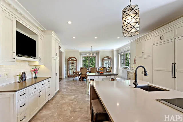 a large white kitchen with a large window and stainless steel appliances