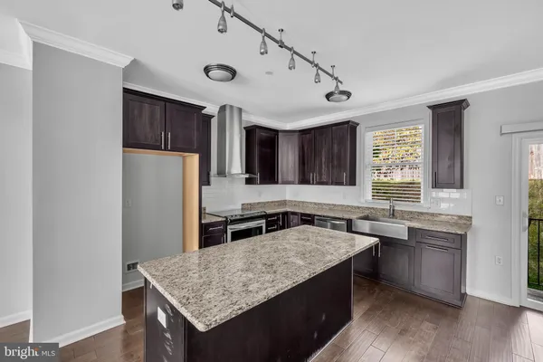 a kitchen with granite countertop a stove a sink dishwasher a refrigerator and wooden cabinets with wooden floor