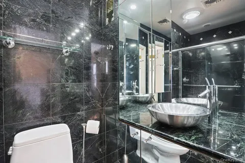 a bathroom with a granite countertop sink a toilet a mirror and bathtub